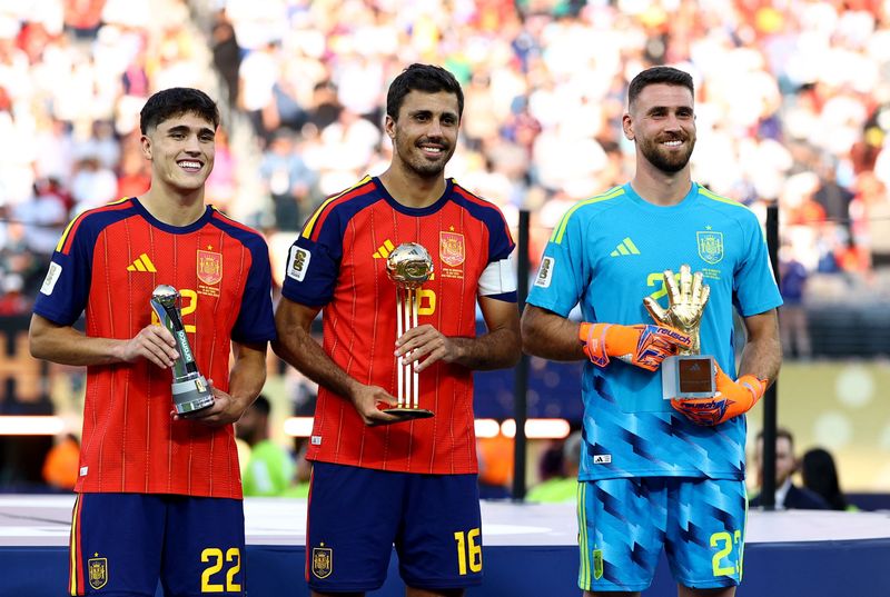 Pau Cubarsi, Rodri, Unai Simon Soccer Football - FIFA World Cup 2026 - Final - Spain v Argentina - New York/New Jersey Stadium, East Rutherford, New Jersey, U.S. - July 19, 2026 Spain's Rodri celebrates on the podium after winning the Golden Ball with Golden Glove winner Unai Simon and FIFA Young Player winner Pau Cubarsi following winning the World Cup REUTERS/Kai Pfaffenbach