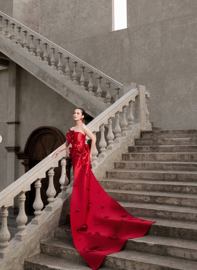 Dea tampil dengan gaun strapless merah dari SIP Studio. Gaun tersebut memiliki siluet yang membentuk tubuh di bagian atas. Sementara bawah gaun dibuat memanjang membentuk train atau ekor yang menjuntai hingga ke lantai. Ekor gaun dihiasi ornamen bunga senada dan membentuk siluet megah, menciptakan efek dramatis. Foto: Instagram/@deaaannisa