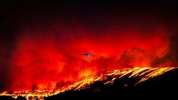 Karya Ekrem Kalkan. Selama kebakaran hutan besar di Çanakkale, Turki, api menyebar di hutan dan lahan pertanian selama tiga hari sebelum akhirnya berhasil dikendalikan. Lebih dari 4.000 hektar lahan terbakar saat helikopter, pesawat terbang, dan tim darurat bekerja untuk memadamkan api. Dalam gambar ini, sebuah helikopter terbang sendirian di atas punggung bukit yang terbakar di bawah langit yang dipenuhi asap dan api. Pemandangan ini mencerminkan skala kerusakan lingkungan dan dampak yang semakin besar dari bencana terkait iklim. Foto: HIPA