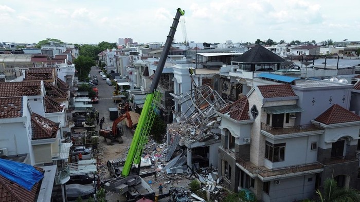 Foto udara petugas mengoperasikan alat berat saat melakukan pencarian korban ledakan di Komplek Grand Polonia, Medan, Sumatera Utara, Selasa (21/7/2026). Berdasarkan data dari Basarnas Medan, akibat ledakan  yang diduga dari pipa gas tersebut satu or