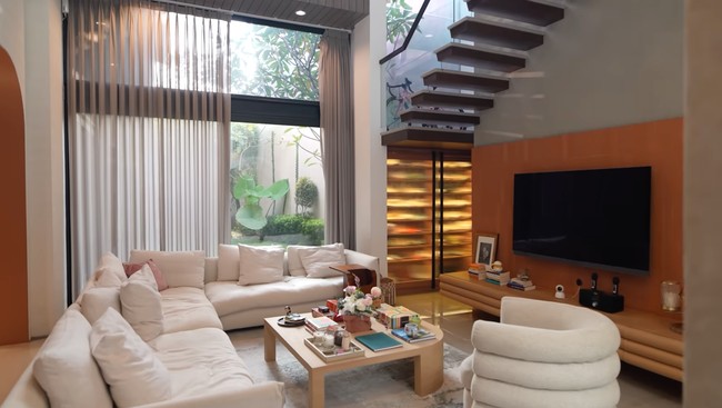 Salah satu ruangan yang menjadi favorit Pevita, living room. Ruangan tersebut tampak cozy dengan sofa putih panjang, televisi, serta meja yang dipakai untuk meletakkan beberapa board game milik Pevita. Foto: YouTube/Pevita Pearce