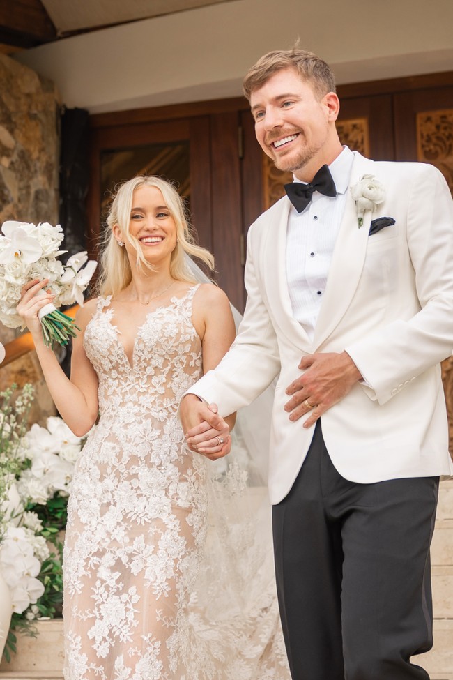 Di hari bahagianya, MrBeast dan Thea tampil serasi dalam balutan busana pengantin bernuansa putih. Thea mengenakan gaun putih rancangan Nicole + Felicia Couture, sementara MrBeast memilih tuksedo dari Ralph Lauren. Foto: Instagram/@mrbeast