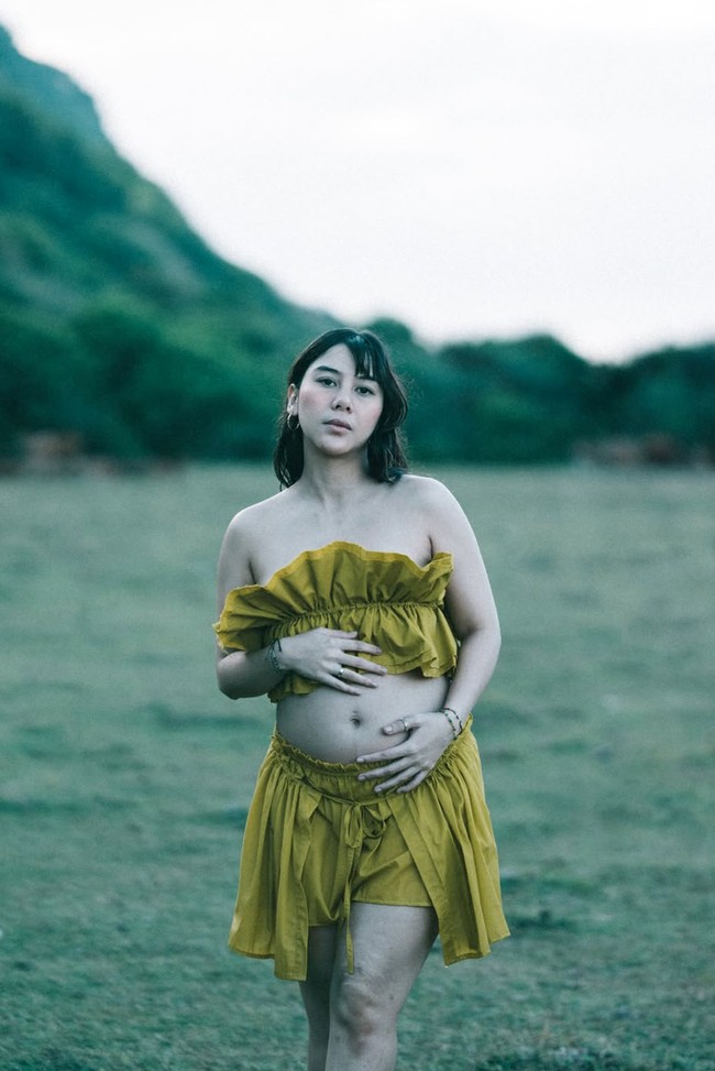 Adinda tampil mengenakan set two-piece bernuansa mustard. Bagian atas busana berupa crop top off-shoulder yang dihiasi detail ruffle bertumpuk pada bagian dada. Atasan tersebut dipadukan dengan rok celana mini berpotongan high-waist yang juga memiliki aksen ruffle bertingkat. Foto: Instagram/@adindathomas