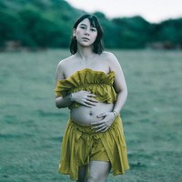 Adinda tampil mengenakan set two-piece bernuansa mustard. Bagian atas busana berupa crop top off-shoulder yang dihiasi detail ruffle bertumpuk pada bagian dada. Atasan tersebut dipadukan dengan rok celana mini berpotongan high-waist yang juga memiliki aksen ruffle bertingkat. Foto: Instagram/@adindathomas