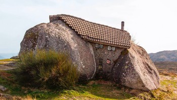 Casa do Penedo di Portugal dijuluki rumah batu karena dibangun di antara empat bongkahan batu granit raksasa. Bentuknya membuat bangunan ini tampak menyatu dengan lanskap pegunungan di sekitarnya. Foto: Weird Buildings via DesignBoom