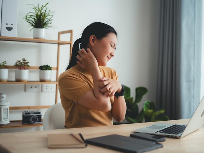 Asian woman suffering from irritate dry skin and scratching her skin sitting at home office.