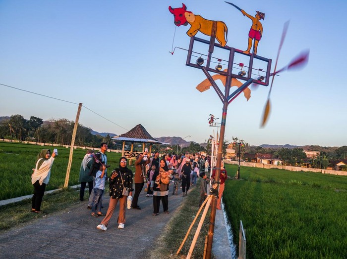 Pengunjung mengamati instalasi kitiran saat Festival Kitiran Sriharjo 2026 di Bulak Truli, Sriharjo, Imogiri, Bantul, DI Yogyakarta, Sabtu (25/7/2026). Festival Kitiran Sriharjo diikuti 63 rukun tetangga (RT) dengan menampilkan ribuan kitiran di area persawahan sebagai upaya melestarikan permainan tradisional, promosi desa wisata Sriharjo serta menggerakkan ekonomi masyarakat melalui pemberdayaan UMKM dan sentra kerajinan kitiran. ANTARA FOTO/Rahid Putra Laksana/agr/nym.