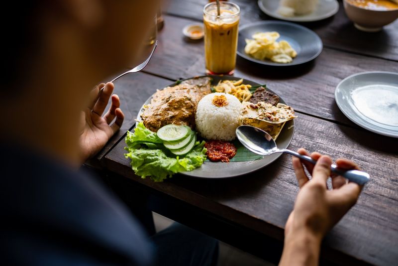 Nasi Pecel, Traditional Indonesian meal with rice, chicken, and sambal served on a wooden table