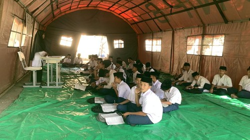 Puluhan siswa kelas 9 Mts Nujumul Huda di Kecamatan Lembar, Lombok Barat, belajar di tenda, Selasa (28/7/2026) akibat ruang kelas hangus terbakar. (Foto: M. Zahiruddin/detikBali)