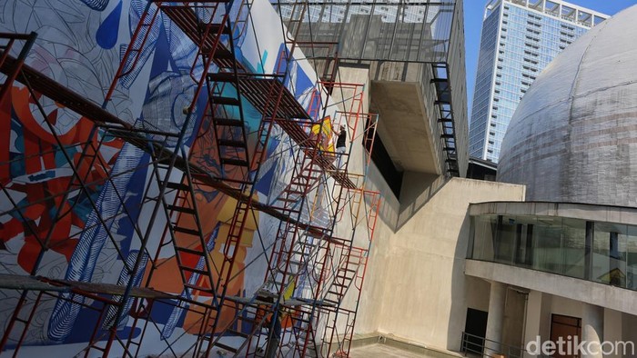 Taman Ismail Marzuki (TIM), Jakarta, menjadi ruang kolaborasi lintas negara melalui pembuatan mural bertajuk Interconnected Existence yang dikerjakan oleh seniman asal Ukraina, Vitalii Hrekh atau yang dikenal dengan nama Dilkone, bersama seniman Austria Manuel Skirl dan seniman Indonesia Muna Diannur. Karya tersebut mulai dikerjakan pada Selasa (28/7/2026) dan dijadwalkan rampung pada Kamis (30/7) sebelum dibuka untuk dinikmati publik.