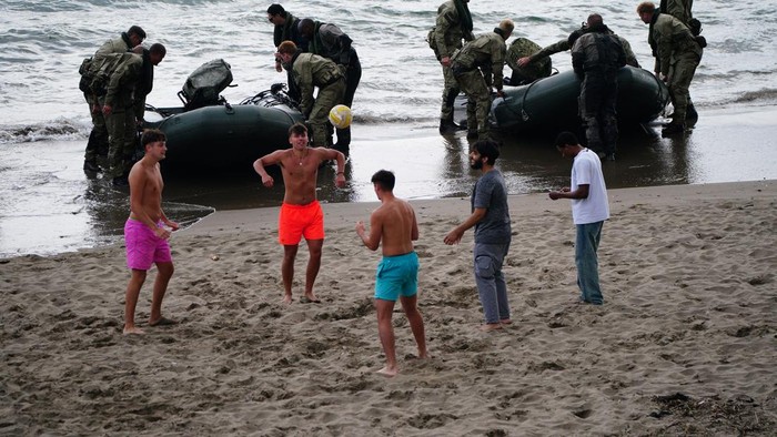 People play on the beach as members of Armed Forces personnel from 47 Commando (Raiding Group) Royal Marines conduct beach landing training at Tregantle Fort, Torpoint southeast Cornwall, using modern-day landing craft, in scenes reminiscent of events on D-Day. The training exercise is based on a contemporary battlefield scenario and comes just a few weeks before 47 Commando land on Gold Beach in Normandy, France, to commemorate the 80th anniversary of D-Day. Picture date: Monday May 20, 2024. (Photo by Ben Birchall/PA Images via Getty Images)