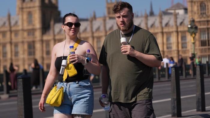 People with portable fans walking along Westminster Bridge in London. The fourth heatwave of the year is set to peak on Wednesday with temperatures of up to 35C, as experts warn wildfires could be 