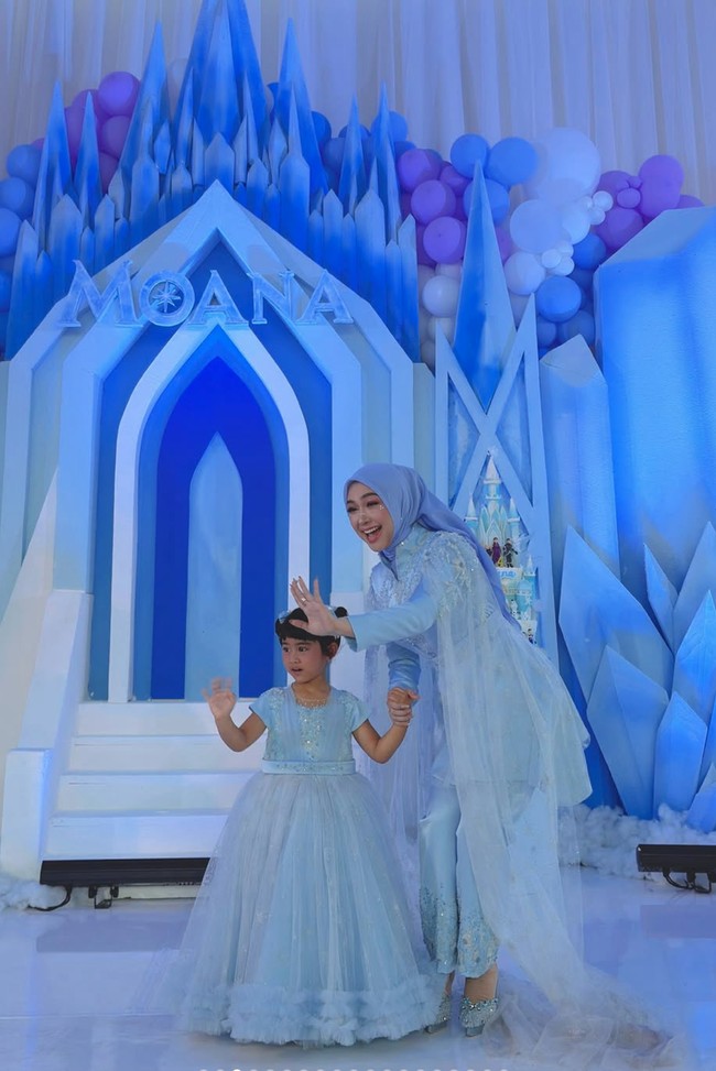 Busana yang dikenakan Ricis tampak elegan dengan bagian dada dan bahu dihiasi bordir atau payet berwarna senada. Busana tersebut juga dilengkapi dengan cape atau selendang panjang berbahan lace/tulle putih yang menjuntai hingga ke bawah. Foto: Instagram/@riaricis1795