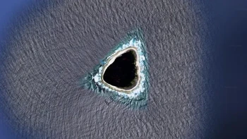 Pulau Vostok, sebuah pulau karang kecil tak berpenghuni yang terletak di Samudra Pasifik tengah, tampak gelap di Google Earth, memicu berbagai teori konspirasi tentangnya — termasuk anggapan bahwa pulau itu adalah pangkalan militer rahasia, beberapa menyebut pulau hantu. Pada kenyataannya, bagian tengah pulau ditutupi oleh pohon Pisonia grandis yang berakar di tanah gambut yang tebal. Pohon-pohon ini sangat lebat dan gelap, sehingga dari atas dedaunan memberikan pulau itu penampilan seperti lubang hitam yang aneh.  Foto: Live Science