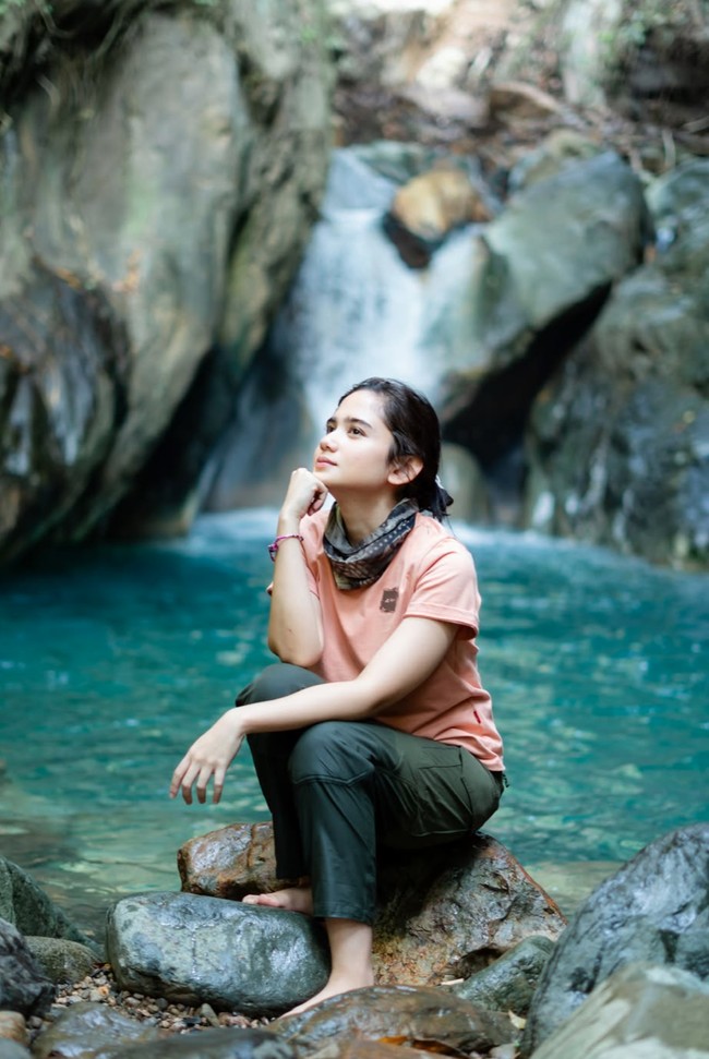 Pose di bawah air terjun, Tissa tampil santai. Ia duduk sambil bertopang dagu di atas tumpukan bebatuan. Foto: Instagram/@tissabiani