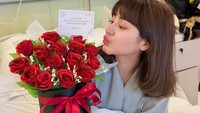 Ghea Youbi berpose dengan salah satu buket bunga mawar merah yang diterimanya. Ia terlihat tersenyum ke arah kamera, meskipun wajahnya tampak sedikit pucat. (Foto: dok Instagram gheayoubi)