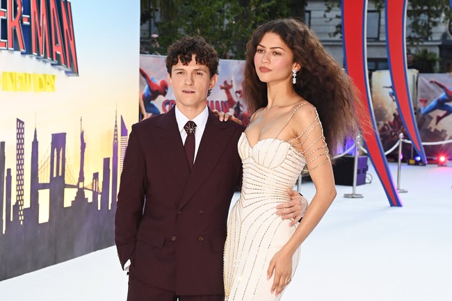 Di sisi lain, Tom Holland tampil tak kalah stylish dengan setelan jas burgundy berpotongan klasik. Warna jasnya berpadu apik dengan nuansa gaun Zendaya, menciptakan couple look yang serasi tanpa harus mengenakan busana kembaran. Foto: PA Images via Getty Images/Ian West - PA Images