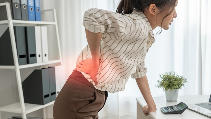 Asia beautiful woman holding her lower back while and suffer from unbearable pain health and problems, chronic back pain, backache in office syndrome, scoliosis, herniated disc, muscle inflammation