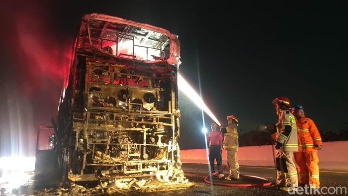 Damkar Nganjuk memadamkan bus Gunung Harta yang terbakar.
