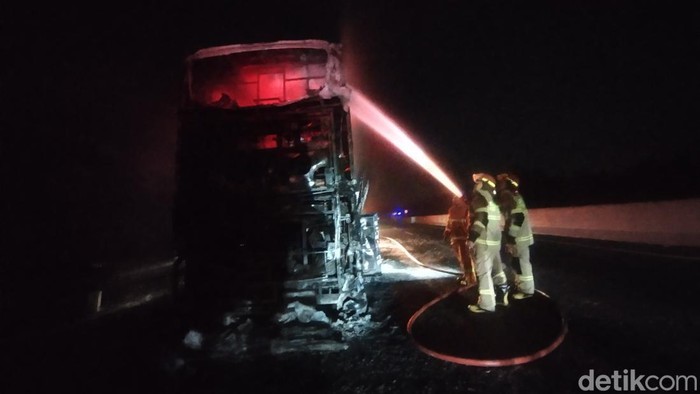 Damkar Nganjuk memadamkan bus Gunung Harta yang terbakar.