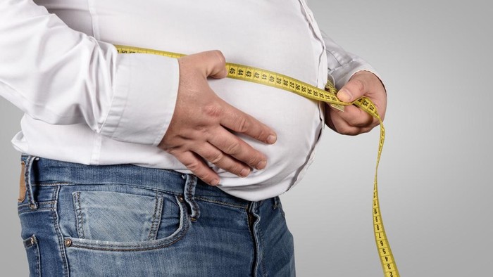 Overweight Man Measuring His Belly with tape measure