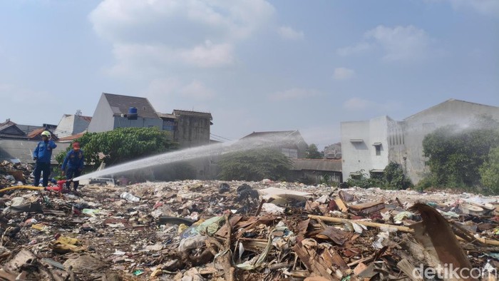 Damkar masih menyemprotkan air ke tempat pembuangan sampah (TPS) liar di Kramat Jati, Jakarta Timur. Api terus disemprotkan agar api padam total. (Kurniawan/detikcom)