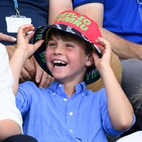 Louis tampaknya tak bisa menolak kesempatan untuk mencoba topi bucket berwarna merah bertuliskan bahasa Wales Beicio Cymru” atau Welsh Cycling. Ia bahkan menarik topi tersebut hingga menutupi matanya sebelum tertawa lepas. Tingkahnya sontak membuat orang-orang di sekitarnya ikut tersenyum. (Foto: Karwai Tang/WireImage)
