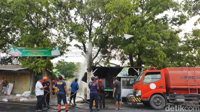 Petugas memadamkan kebakaran warung es dawet di Jalan Sunan Kalijaga Demak, Senin (3/8/2026).