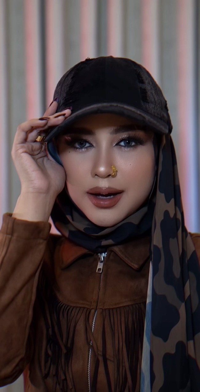 Ria Ricis tampil dengan riasan bergaya baddie makeup. Alisnya dibuat tebal serta rapi dengan bentuk melengkung, dipadukan eyeshadow bernuansa cokelat dan bulu mata lentik yang memberi efek mata lebih tajam. Sentuhan contour, highlighter, dan lipstik cokelat nude membuat keseluruhan riasannya terlihat modern sekaligus elegan. Foto: Instagram/@riaricis1795