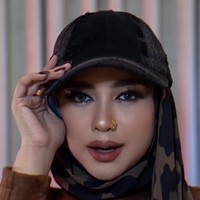 Ria Ricis tampil dengan riasan bergaya baddie makeup. Alisnya dibuat tebal serta rapi dengan bentuk melengkung, dipadukan eyeshadow bernuansa cokelat dan bulu mata lentik yang memberi efek mata lebih tajam. Sentuhan contour, highlighter, dan lipstik cokelat nude membuat keseluruhan riasannya terlihat modern sekaligus elegan. Foto: Instagram/@riaricis1795