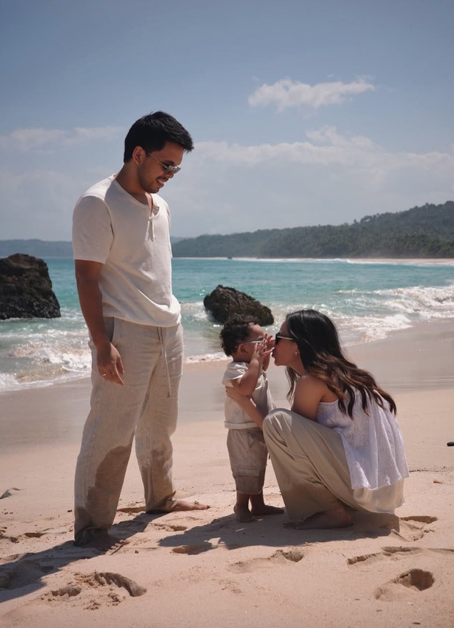 Ketiganya juga menjalani pemotretan di tepi pantai yang memperlihatkan kehangatan keluarga mereka. Kompak bareng mama dan papa, baby Arash juga kenakan busana santai bernuansa putih dan beige. Foto: Instagram/@thariqhalilintar