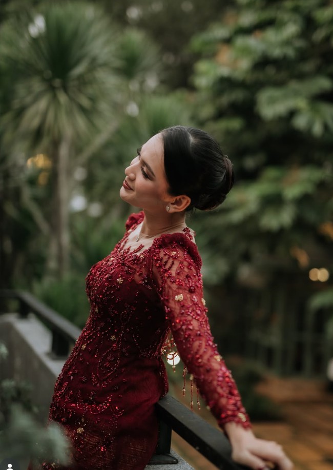 Bagian atas kebaya dipenuhi bordir tiga dimensi (3D embroidery) bermotif floral dan sulur yang dipadukan dengan taburan payet merah serta sentuhan aksen keemasan. Detail ini membuat busana terlihat berkilau ketika terkena cahaya tanpa tampak berlebihan. Foto: Instagram/@deaaannisa