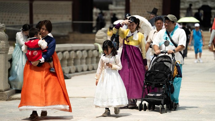 SEOUL, SOUTH KOREA - AUGUST 05: Tourists clad in traditional Korean hanbok attire use hand fans and umbrellas to shelter themselves from the summer heat as they stroll through the grounds of Gyeongbokgung Palace in Seoul, South Korea, on August 05, 2026. (Photo by Hwawon Lee/Anadolu via Getty Images)