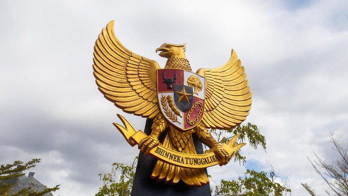 Gold Garuda Pancasila, Indonesian national emblem on blue and cloudy sky background.