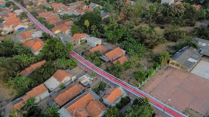 Foto udara seorang anak bersepeda di bawah bendera Merah Putih yang terbentang di Kampung Peundeuy Timur, Desa Karang Satu, Kecamatan Karangbahagia, Kabupaten Bekasi, Jawa Barat, Kamis (6/8/2026). Warga setempat membentangkan bendera Merah Putih sepanjang 500 meter yang dibuat secara gotong royong dengan biaya swadaya sekitar Rp25 juta untuk menyambut HUT ke-81 Kemerdekaan RI. ANTARA FOTO/Darryl Ramadhan/kye