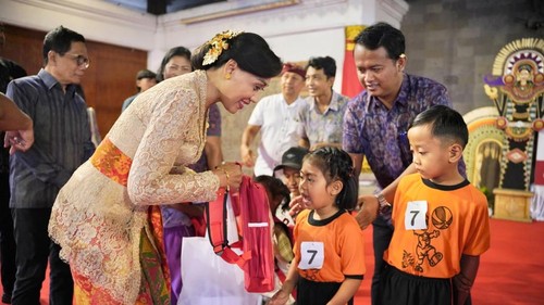 Bunda PAUD Gianyar Surya Adnyani Mahayastra menyerahkan tas sekolah berisi tumbler dan kotak makan serta makanan tambahan saat acara Pawai Kebangsaan PAUD dan Festival PAUD Inklusif di Balai Budaya Gianyar, Sabtu (8/8/2026). (Dok Pemkab Gianyar).