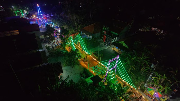 Ornamen lampu hias tematik sambut HUT RI Sejumlah warga berjalan melewati ornamen lampu hias berbentuk Jembatan Suramadu di Desa Kandang, Kecamatan Comal, Kabupaten Pemalang, Jawa Tengah, Sabtu (8/8/2026). Warga bersama Pemerintah Desa Kandang memasang berbagai lampu hias tematik berbentuk Garuda, Jembatan Suramadu, Tugu Monas, dan sejumlah hewan di sepanjang tiga kilometer jalan desa selama Agustus menggunakan dana swadaya masyarakat untuk menyambut HUT ke-81 Kemerdekaan Republik Indonesia sekaligus menarik minat ratusan pelaku UMKM berjualan di lokasi. ANTARA FOTO/Harviyan Perdana Putra/kye