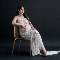 Gaun tersebut memiliki potongan sleeveless dengan bagian bahu terbuka. Tali bahunya dibuat tipis dan juga dihiasi aplikasi bunga kecil. Di antara aplikasi bunga terdapat sedikit ruang transparan yang memberikan kesan semi-sheer atau semi-transparan. Foto: Instagram/@adindathomas
