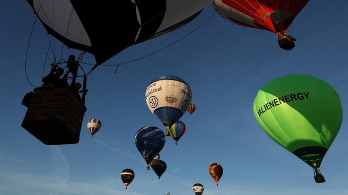 Hot air balloons fly near a fairground attraction during a mass launch at the annual Bristol International Balloon Fiesta, Bristol, Britain, August 8, 2026. REUTERS/Toby Melville