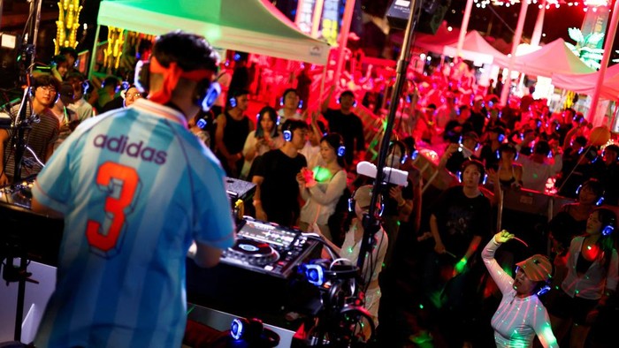 People wearing wireless headphones dance during 
