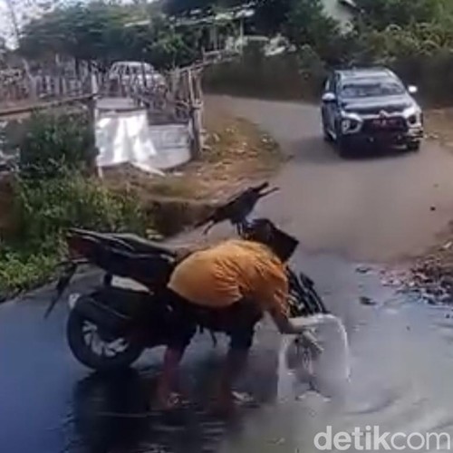 Aksi seorang pria Desa Mata, Kecamatan Tarano, Kabupaten Sumbawa yang mencuci motor di kubangan saat mobil Wabup Sumbawa melintas.