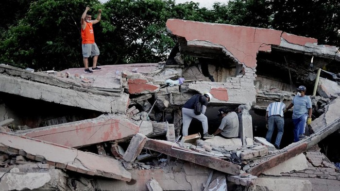 A rescue worker raises his fists to call for silence to locate victims under the rubble at the site of a collapsed building following an earthquake, in Cali, Colombia, August 10, 2026. REUTERS/Sergio Acero