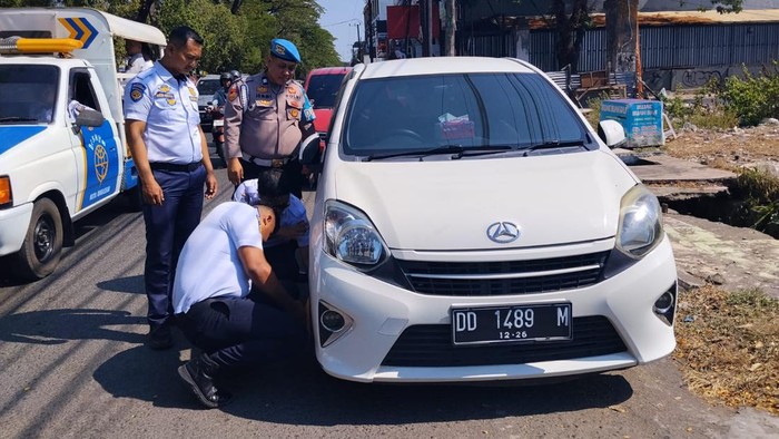 Dishub Makassar menggombok mobil parkir bahu jalan di Jalan Veteran, Makassar.