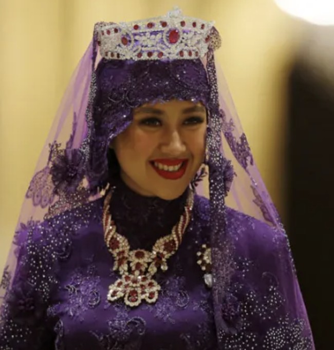 Pada bagian kepala, Raabiatul juga mengenakan veil transparan dengan tiara kedua yang dihiasi berlian, rubi, dan batu berwarna merah di bagian tengah. Ia melengkapi penampilan dengan kalung model rope yang juga bertabur berlian. Foto: dok. Reuters