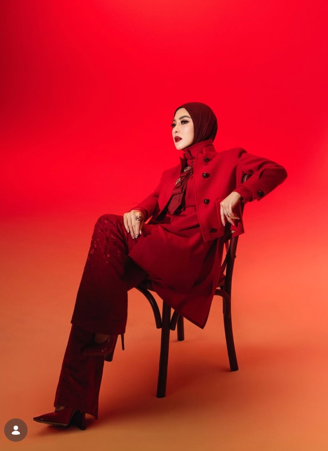 Penyanyi 46 tahun itu tampil dengan atasan merah berkerah tinggi dipadukan luaran menyerupai jaket dan celana panjang senada. Penampilannya semakin lengkap dengan hijab polos yang juga berwarna merah. Foto: Instagram/@princessyahrini