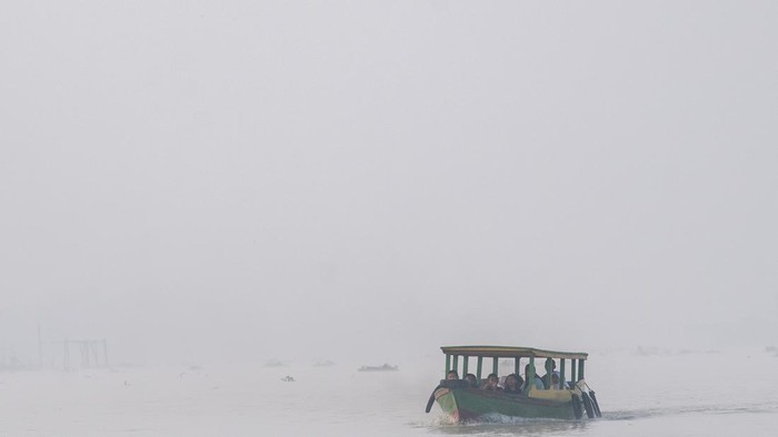 Sejumlah pelajar berangkat sekolah menggunakan perahu tradisional melewati kawasan yang diselimuti kabut asap di Sungai Ogan, Palembang, Sumatera Selatan, Kamis (13/8/2026). Kabut asap tersebut merupakan dampak dari kebakaran hutan dan lahan (Karhutla) yang terjadi di berbagai Kabupaten di Provinsi Sumatera Selatan. ANTARA FOTO/Nova Wahyudi/YU