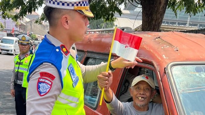 Polantas di Kota Bekasi menyapa pengendara ojol hingga angkot dan membagikan bendera Merah Putih, Kamis (13/8/2026).