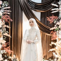 Dea Annisa tampil sangat anggun memadukan gaya hijab putih polos dengan veil renda transparan yang menjuntai cantik. Busana pengantin bernuansa putih dengan detail bordir floral lembut dan aksen jubah tulle ini makin mempertegas kesan dreamy serta elegan di hari bahagianya. Foto: Dok. Instagram @deaaannisa.