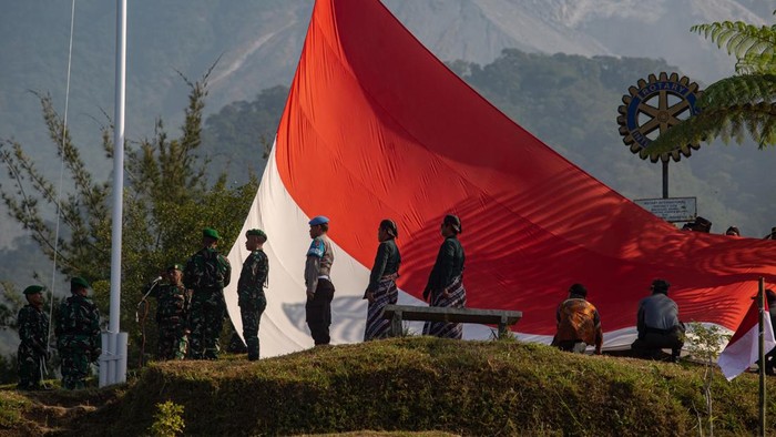 Petugas membawa Bendera Merah Putih raksasa yang akan dikibarkan saat upacara di lereng Gunung Merapi, Bukit Klangon, Cangkringan, Sleman, D.I. Yogyakarta, Minggu (16/8/2026). Pengibaran Bendera Merah Putih berukuran 9x6 meter tersebut diikuti ribuan peserta dari berbagai elemen masyarakat dalam memperingati HUT ke-81 RI.   ANTARA FOTO/Andreas Fitri Atmoko