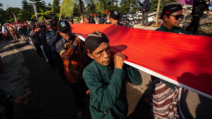 Petugas membawa Bendera Merah Putih raksasa yang akan dikibarkan saat upacara di lereng Gunung Merapi, Bukit Klangon, Cangkringan, Sleman, D.I. Yogyakarta, Minggu (16/8/2026). Pengibaran Bendera Merah Putih berukuran 9x6 meter tersebut diikuti ribuan peserta dari berbagai elemen masyarakat dalam memperingati HUT ke-81 RI.   ANTARA FOTO/Andreas Fitri Atmoko